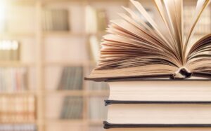 Open book on top of stack of books in library