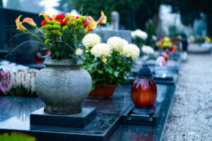 Fog going up in the morning, quiet path on a graveyard, grave with beautiful flowers and a candle
