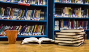 Books open on a table in library with coffee cup